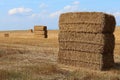 Stacked large rectangular hay bales placed on field after harvest, blue skies with some clouds in background Royalty Free Stock Photo