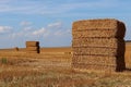 Stacked large rectangular hay bales placed on field after harvest, blue skies with some clouds in background Royalty Free Stock Photo