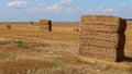 Stacked large rectangular hay bales placed on field after harvest, blue skies with some clouds in background Royalty Free Stock Photo