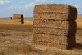 Stacked large rectangular hay bales placed on field after harvest, blue skies with some clouds in background Royalty Free Stock Photo