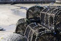 stacked lobster pots on a pier overlooking a beach with the tide out