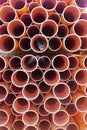 Stacked orange electrical conduit pipes end on