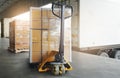 Stacked of Package Boxes on pallet with Hand Pallet Truck. Trailer Truck Parked Loading at Dock Warehouse. Cargo Shipment Boxes.