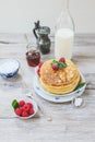 Stacked pancakes raspberries mint and sugar on white plate