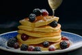 Stacked pancakes with summer berries and falling honey syrup