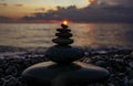 Pyramid or tower of pebble stones with sun against the background of the sea and the sunset sky. Zen stones, meditation concept Royalty Free Stock Photo