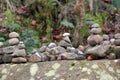 Stacked pebbles and rocks on a large moss covered boulder in autumn woodland
