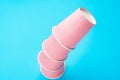 Stacked pink drinking paper cup turned upside down on light blue background. Birthday party celebration kids fun