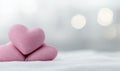 Stacked pink heart-shaped plushies on white surface with blurred light backdrop Royalty Free Stock Photo