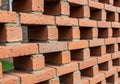 Stacked red bricks with gray mortar, arranged in a staggered pattern creating gaps. Royalty Free Stock Photo