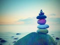 Stacked rounded stones at sea. Polished pebbles on dark wet rock, smooth water