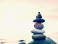 Stacked rounded stones at sea. Polished pebbles on dark wet rock, smooth water