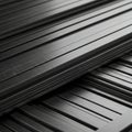 Stacked sheets of black metal feature parallel grooves, creating a textured, sleek Royalty Free Stock Photo