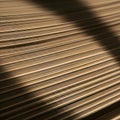 Stacked sheets of light brown paper creating a linear pattern with light and shadow