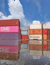 Stacked shipping containers reflect in puddle