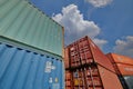 Stacked shipping containers soars into blue sky, some clouds