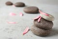 Stacked spa stones with flower petals on grey table Royalty Free Stock Photo