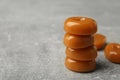 Stacked tasty hard toffee candies on light grey table, closeup. Space for text