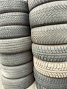 Stacked tires showcasing various tread designs in a tire yard under bright sunlight during the day Royalty Free Stock Photo