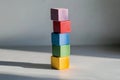 A stacked tower of multi-colored cubes on a light gray surface, with each cube casting a different