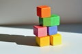 A stacked tower of multi-colored cubes on a light gray surface, with each cube casting a different