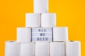 Stacked tower of soft toilet paper rolls, lightened board with All We need message between rolles on bright yellow background.