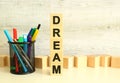 Stacked vertically wooden cubes with letters in the word DREAM on a white work table on a textured gray background. Royalty Free Stock Photo