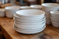 Stacked white bowls on a wooden table in a cozy kitchen setting Royalty Free Stock Photo