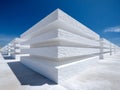 Stacked white foam panels arranged in a geometric pattern under a clear blue sky casting sharp shadows on a smooth concrete Royalty Free Stock Photo