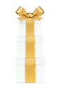 Stacked white gift boxes wrapped with gold ribbon and bow isolated on white