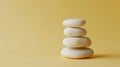 Stacked white smooth stones on yellow background