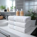 Stacked white towels under a counter in a white bathroom