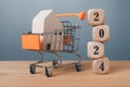 Stacked wooden blocks with 2024 numbers and a cart inside with a wooden house, home sale target concept Royalty Free Stock Photo