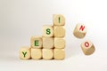 Stacked wooden cubes with the word YES, two are falling with NO, concept for a positive decision Royalty Free Stock Photo