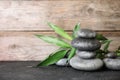 Stacked zen stones and bamboo leaves on table against wooden background Royalty Free Stock Photo