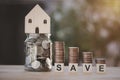 Stacking of coins and a glass jar with house model on top, wood concept SAVE under coins stack show idea save money Royalty Free Stock Photo