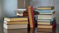 Stacks of books are on the table. A book with a red cover stands between stacks of books. Background for libraries, education,