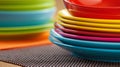 Stacks of brightly colored plates arranged on a textured table surface in a warm kitchen Royalty Free Stock Photo