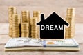 Stacks of coins and dollar bills, blackboard in the shape of a house with text & x22;DREAM& x22; Royalty Free Stock Photo