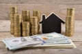 Stacks of coins and dollar bills, blank blackboard in the shape of a house Royalty Free Stock Photo