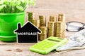 Stacks of coins and dollar bills, calculator, blackboard in the shape of a house with text & x22;MORTGAGE& x22; Royalty Free Stock Photo