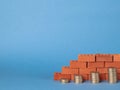 Stacks of coins in the form of steps against a background of blocks of red bricks. Royalty Free Stock Photo