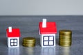 Stacks of coins symbolizing different costs next to two miniature houses of different sizes Royalty Free Stock Photo