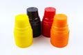 Stacks of colorful plastic cups, yellow, black, red and orange cups on white background Royalty Free Stock Photo