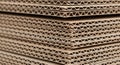 Stacks of corrugated cardboard sheets are shown, featuring a wavy inner layer sandwiched between Royalty Free Stock Photo