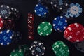 Stacks of different colored poker chips and playing dices on the casino table isolated over black background. Gambling tournament Royalty Free Stock Photo