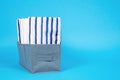 Stacks different white and striped bed linen on blue background. concept organized storage of clothes