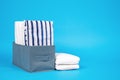 Stacks different white and striped bed linen on blue background. concept organized storage of clothes