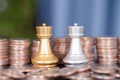 Stacks of dollar coins in front of the two chess pieces in a duel Royalty Free Stock Photo