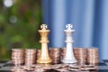 Stacks of dollar coins before the two chess kings of both sides in a duel Royalty Free Stock Photo